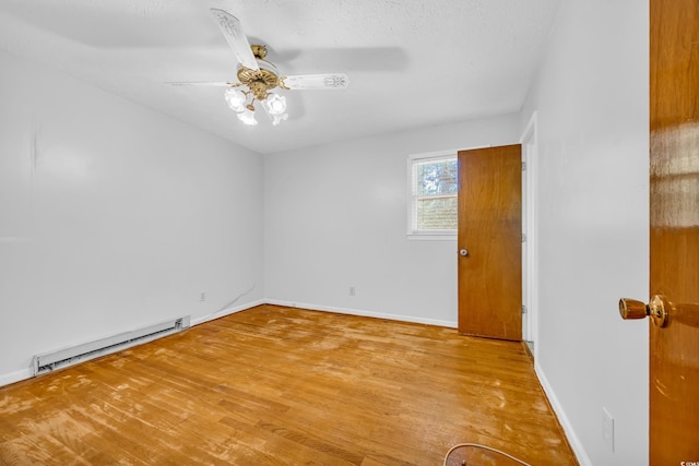 unfurnished room featuring baseboard heating, light wood-type flooring, and baseboards