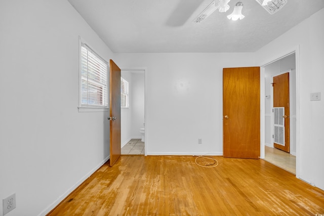 unfurnished bedroom with light wood-style floors, baseboards, and connected bathroom