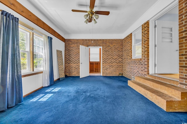 empty room featuring brick wall, carpet floors, and ceiling fan