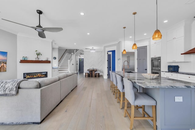 260 Palmetto Harbour Dr, North Myrtle Beach, SC 29582 - living area with stairs, light wood finished floors, a glass covered fireplace, ornamental molding, and recessed lighting