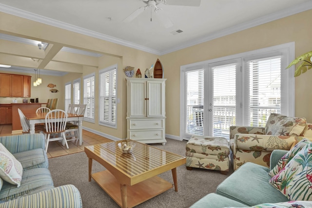 living room with a ceiling fan, visible vents, crown molding, baseboards, and light tile patterned flooring