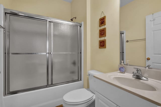 bathroom with toilet, combined bath / shower with glass door, and vanity