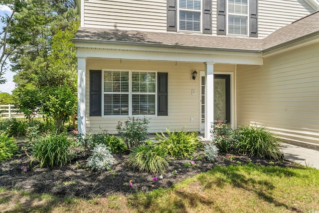 entrance to property with roof with shingles and a porch