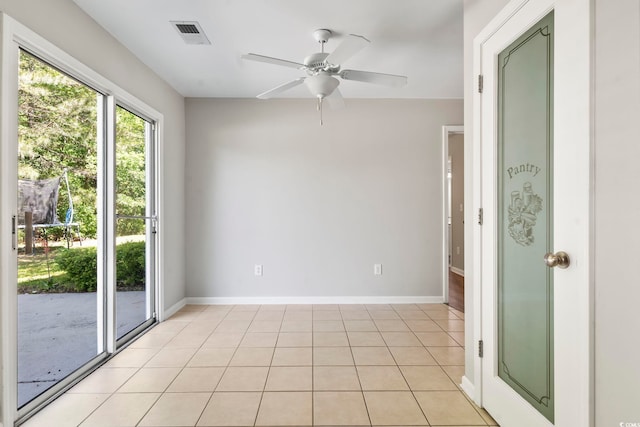 spare room featuring light tile patterned flooring, ceiling fan, visible vents, and baseboards