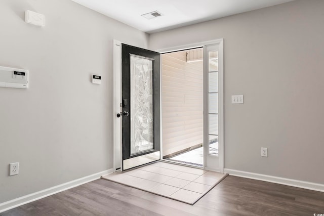 interior space with baseboards, wood finished floors, and visible vents