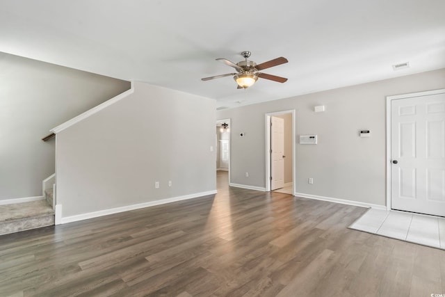 unfurnished living room featuring visible vents, wood finished floors, baseboards, stairway, and a ceiling fan
