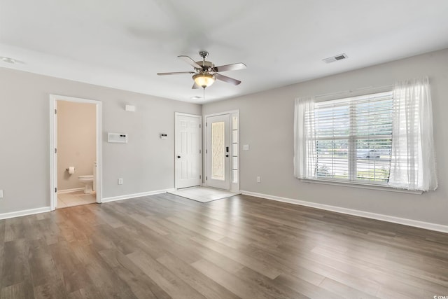 interior space featuring baseboards, a ceiling fan, wood finished floors, and visible vents