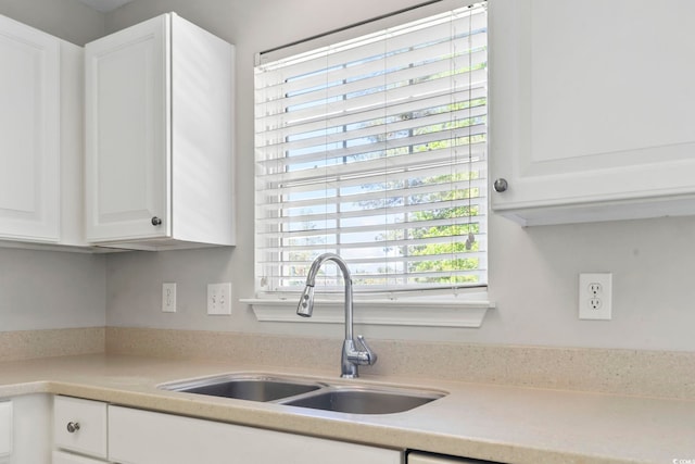 kitchen with light countertops, white cabinetry, and a sink