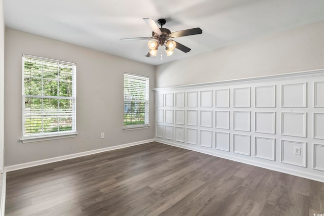 unfurnished room featuring baseboards, a ceiling fan, and dark wood-style floors