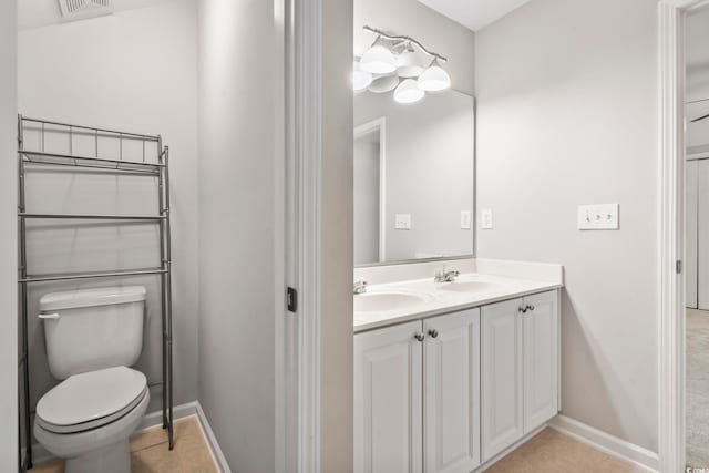 bathroom featuring double vanity, toilet, baseboards, and a sink