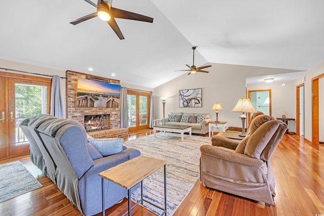 living area with a fireplace, ceiling fan, lofted ceiling, and light wood finished floors