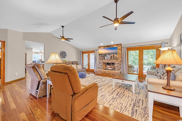 living room with french doors, a fireplace, light wood-type flooring, ceiling fan, and lofted ceiling