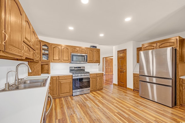 kitchen featuring a sink, brown cabinets, light wood-style flooring, light countertops, and appliances with stainless steel finishes