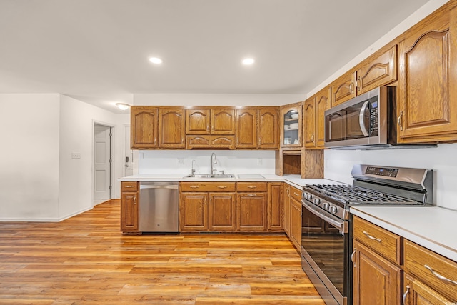 kitchen with light countertops, stainless steel appliances, brown cabinetry, and a sink