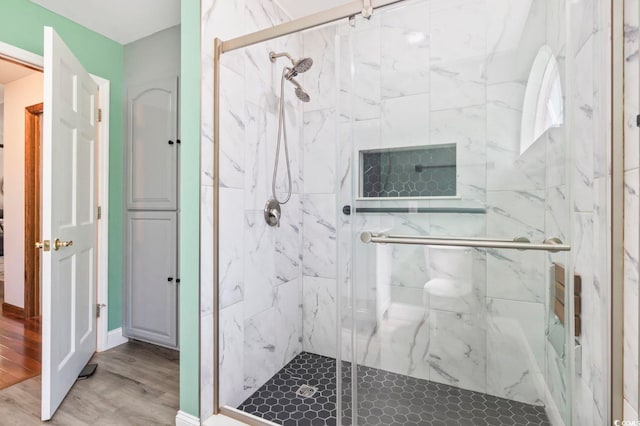 full bath featuring a marble finish shower and wood finished floors