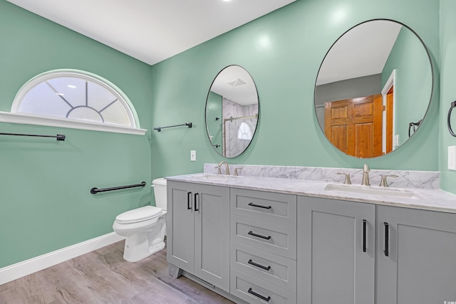 bathroom featuring toilet, baseboards, a sink, and wood finished floors