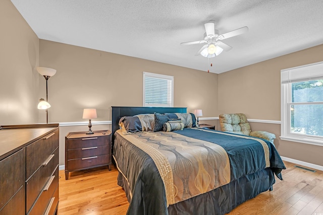 bedroom featuring a textured ceiling, baseboards, visible vents, and light wood-style floors