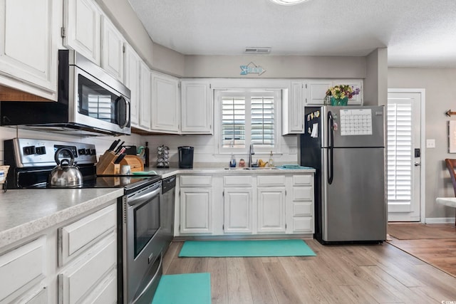 kitchen featuring a sink, light countertops, stainless steel appliances, and visible vents