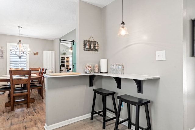 kitchen featuring light wood-style floors, pendant lighting, a breakfast bar area, and ceiling fan with notable chandelier
