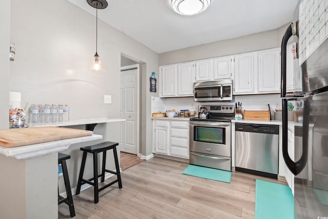 634 Cypress Ln, North Myrtle Beach, SC 29582 - kitchen featuring stainless steel appliances, light countertops, white cabinetry, light wood-style floors, and decorative light fixtures