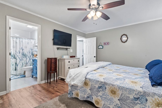 bedroom with ceiling fan, wood finished floors, baseboards, ornamental molding, and ensuite bath