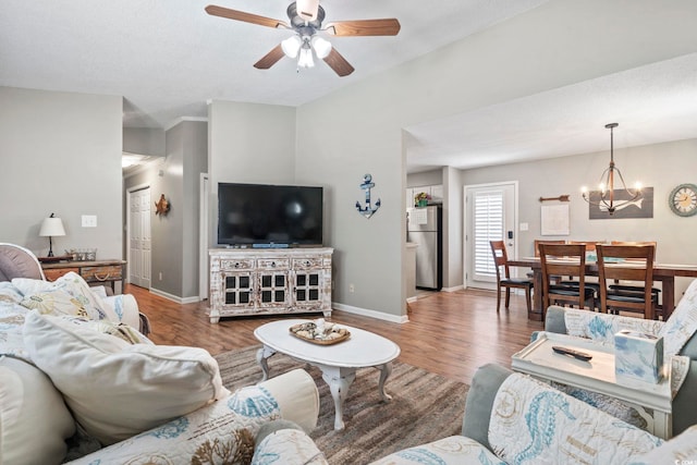 living room with baseboards, ceiling fan with notable chandelier, and wood finished floors