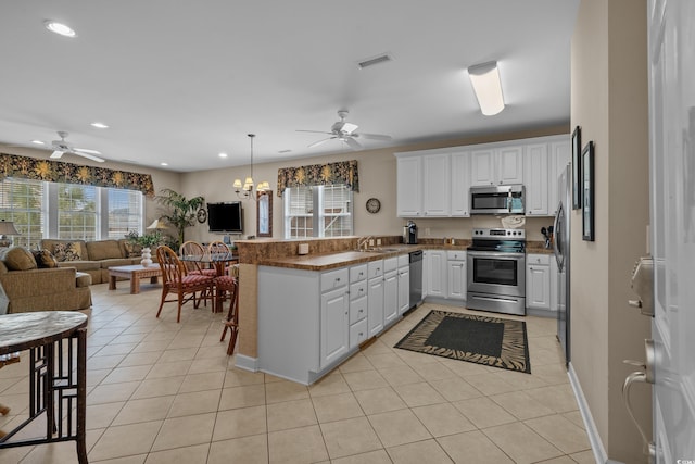 215-B S Dogwood Dr, Surfside Beach, SC 29575 - kitchen with a peninsula, ceiling fan with notable chandelier, open floor plan, appliances with stainless steel finishes, and light tile patterned floors