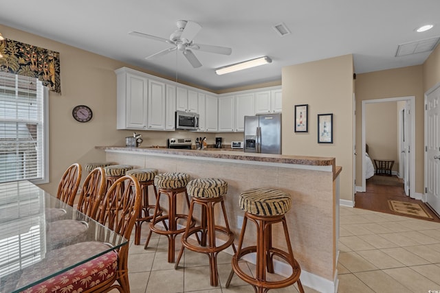 215-B S Dogwood Dr, Surfside Beach, SC 29575 - kitchen featuring a ceiling fan, a peninsula, light tile patterned floors, and stainless steel appliances