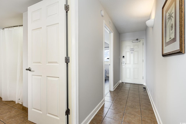 corridor with baseboards, tile patterned flooring, and visible vents