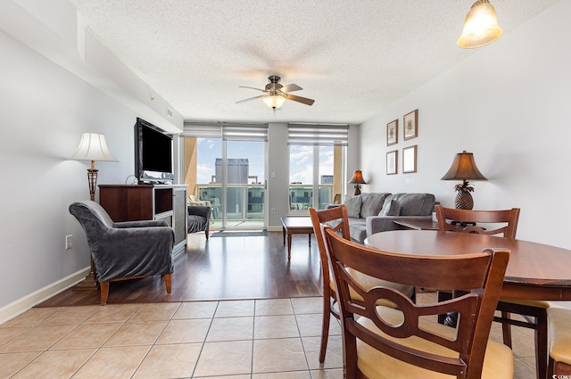 living room featuring a textured ceiling, ceiling fan, baseboards, and light wood finished floors