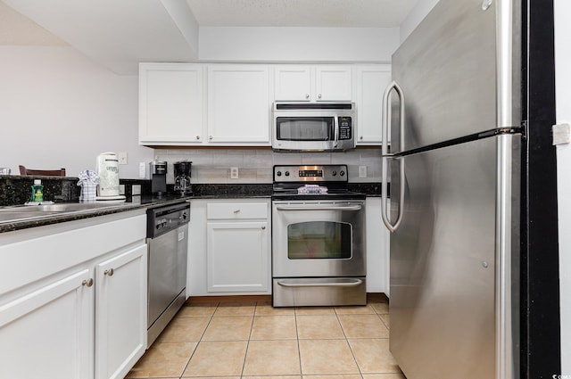 kitchen featuring light tile patterned floors, white cabinets, stainless steel appliances, and tasteful backsplash