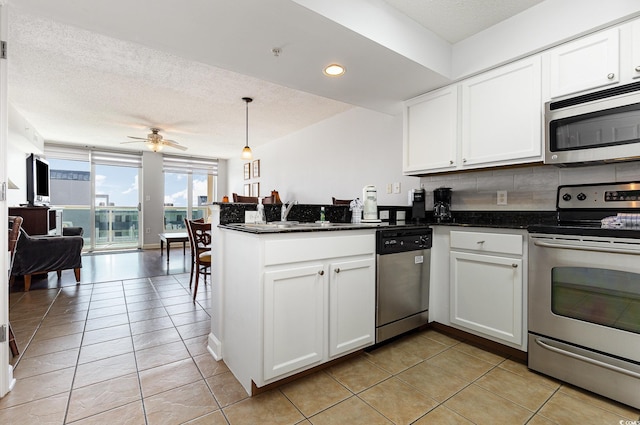 kitchen with white cabinets, a peninsula, ceiling fan, and appliances with stainless steel finishes