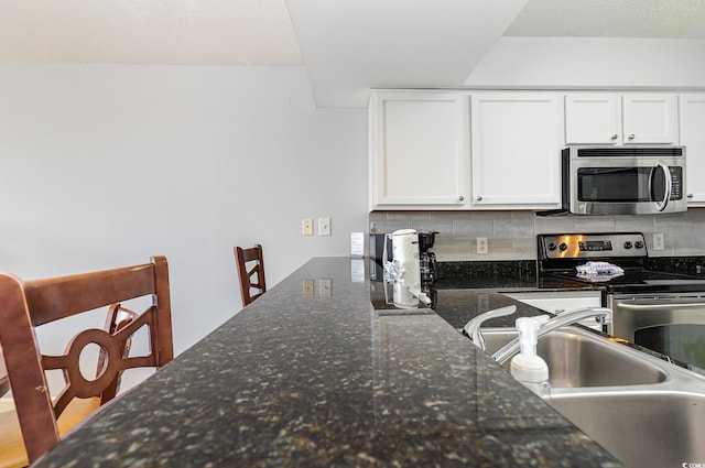 1707 Perrin Dr Unit 802, North Myrtle Beach, SC 29582 - kitchen with appliances with stainless steel finishes, backsplash, white cabinets, a sink, and dark stone countertops