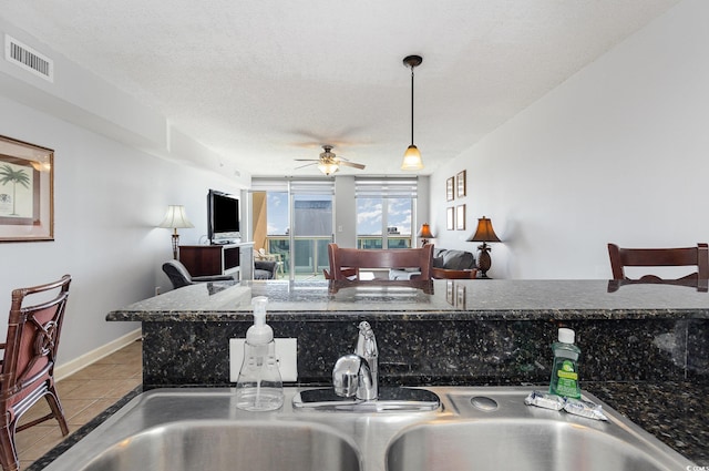 kitchen with ceiling fan, a sink, tile patterned flooring, decorative light fixtures, and visible vents