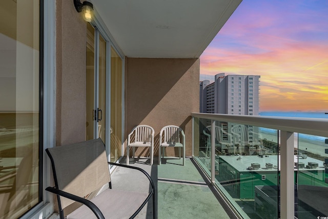 balcony at dusk featuring a view of city