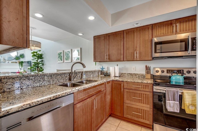 kitchen featuring light tile patterned flooring, light stone countertops, appliances with stainless steel finishes, and a sink