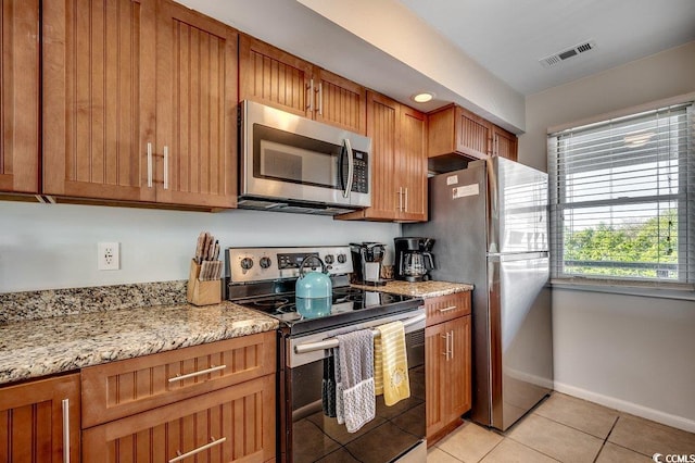kitchen with visible vents, appliances with stainless steel finishes, brown cabinets, light tile patterned floors, and baseboards