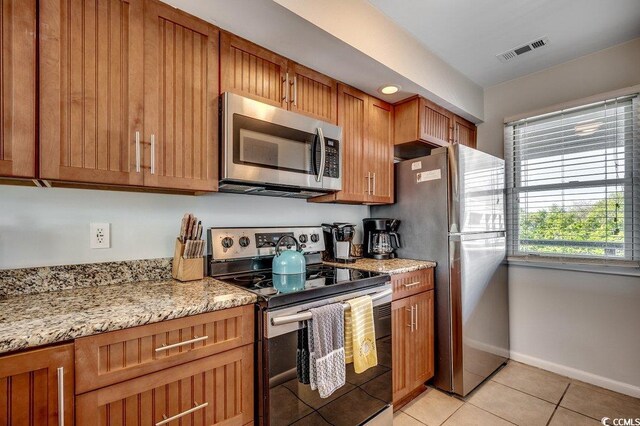 201 N Hillside Dr Unit 311-A, North Myrtle Beach, SC 29582 - kitchen with visible vents, appliances with stainless steel finishes, brown cabinets, light tile patterned floors, and baseboards
