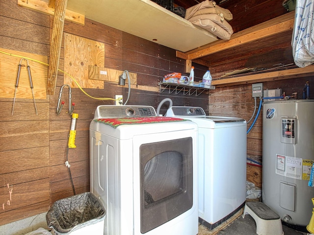 laundry room with water heater, laundry area, wooden walls, and washer and clothes dryer