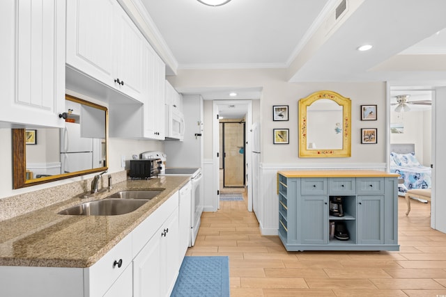 kitchen featuring wood tiled floor, a sink, ornamental molding, white appliances, and white cabinetry