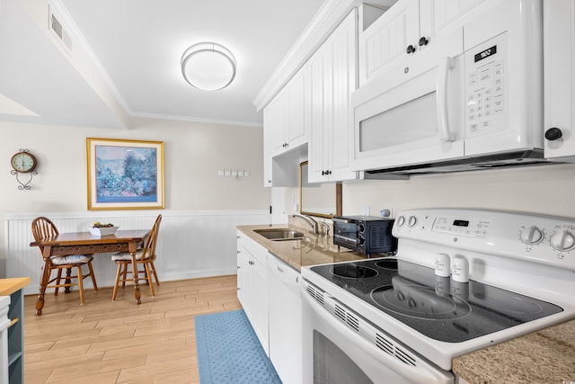 kitchen with ornamental molding, white appliances, light wood-type flooring, white cabinetry, and a sink
