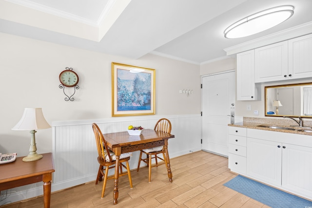 dining room with wainscoting, ornamental molding, and light wood-style floors