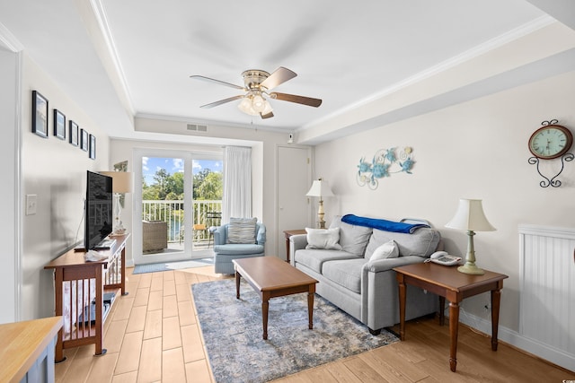 living room with crown molding, a ceiling fan, light wood-style flooring, and visible vents