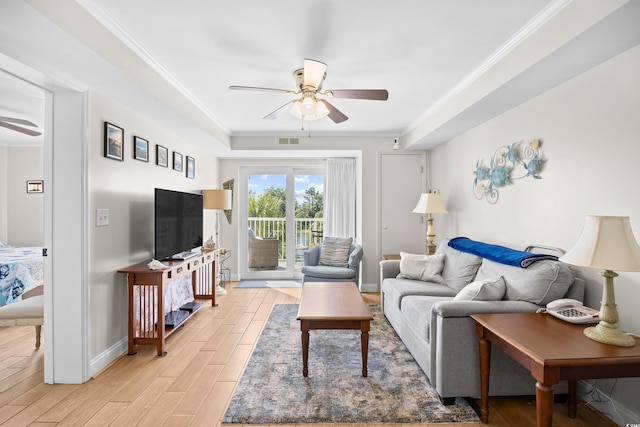 living room featuring crown molding, light wood-style flooring, a ceiling fan, baseboards, and visible vents