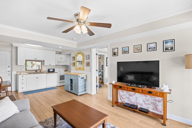 living area featuring light wood-style floors, baseboards, ceiling fan, and crown molding