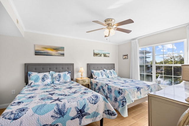bedroom with crown molding, a ceiling fan, a water view, and light wood-style floors