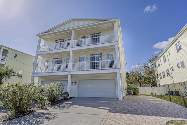 view of front of home featuring a garage, fence, a balcony, concrete driveway, and central air condition unit