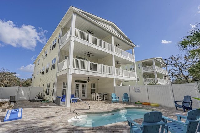 rear view of house featuring ceiling fan, a fenced in pool, a fenced backyard, french doors, and a patio