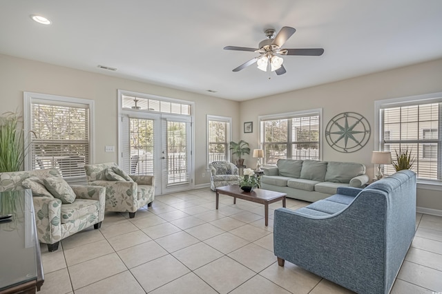 living area with light tile patterned flooring, a ceiling fan, visible vents, and baseboards