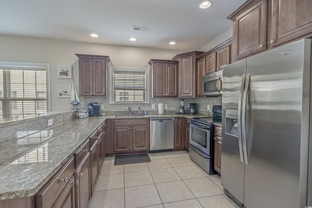 kitchen with visible vents, appliances with stainless steel finishes, a sink, a peninsula, and light tile patterned flooring